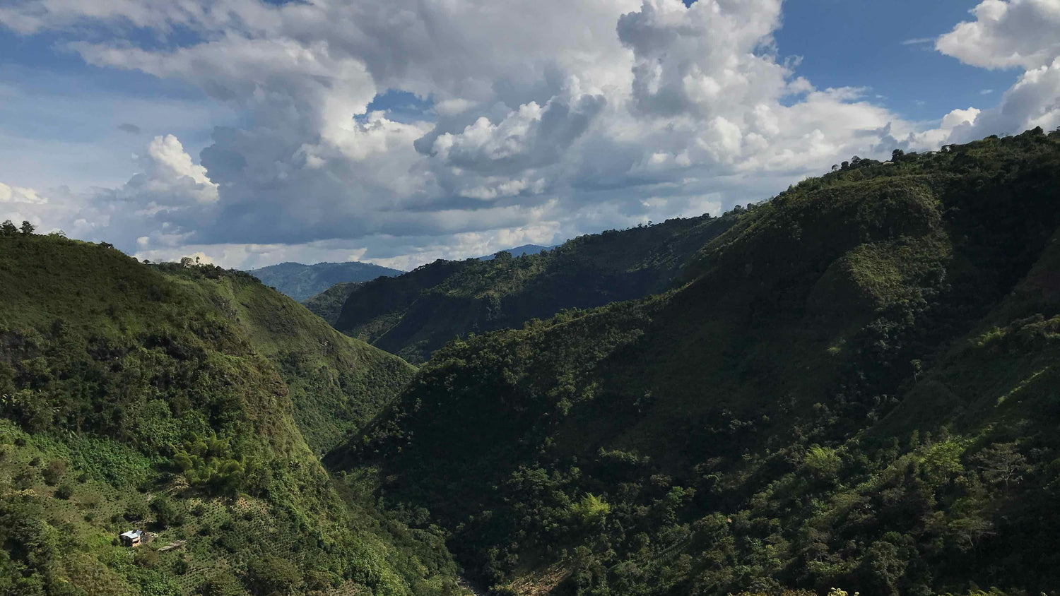 Valley with green hills and a blue sky with clouds